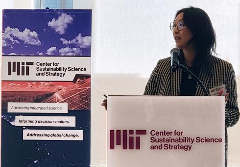 Amanda Giang presents at the podium of Global Change Forum 47, with MIT CS3  banner in the background.